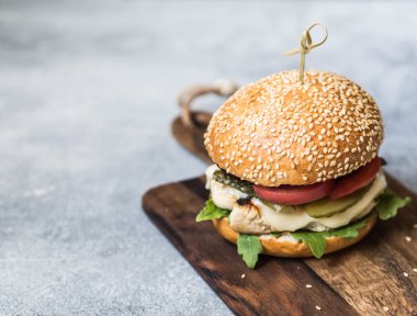 Ev yapımı Hamburger ızgara tavuk, roka, peyniri ve sebze gri bir arka plan üzerinde bir gemide. Kopya alanı