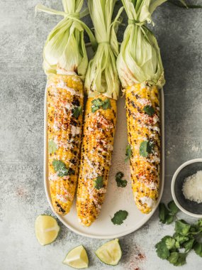 Mısır koçanı sos, kişniş, kireç, kırmızı biber ve seramik bir oval tabak peynirli ızgara. Meksika yemeği. Üstten görünüm