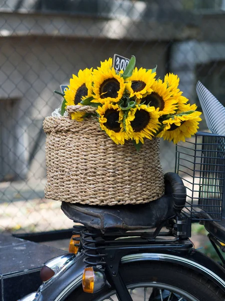 Flowering garden sunflowers in a basket on the seat of a vintage motorcycle in the flower market