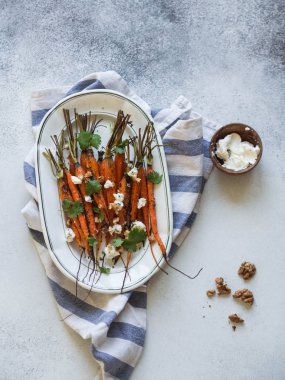 Yumuşak peynir, ceviz ve Salantro beyaz oval plaka üzerinde genç turuncu havuç pişmiş.