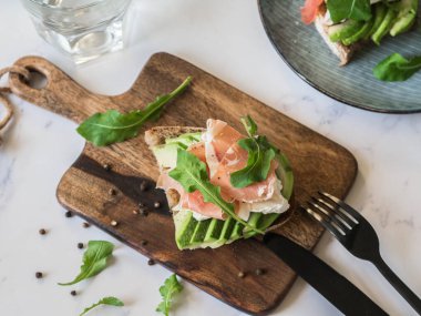 Camembert peyniri, avokado ile tost dilim, prosciutto, roka ve ahşap gemide baharat