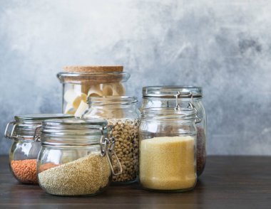 Makarna, mercimek, kuskus, fasulye ve kahverengi ahşap masa üzerinde quinoa ile açık cam kavanoz.