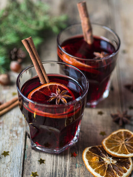 Traditional winter alcoholic drink - mulled wine. Hot wine with fruits and spices in glasses on wooden table