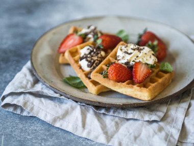 Krema, çikolata ve çilek rustik gri bir arka plan üzerinde gri bir tabakta ile Belçika Waffle.