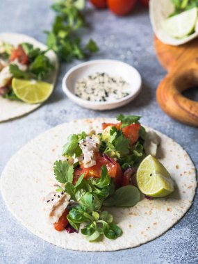 Ekmeği beyaz balık ve sebze ile. Avokado, domates, kırmızı soğan ve cod parça ekmeği gri arka plan üzerine susam ve limon suyu ile serpilir. Meksika yemeği.