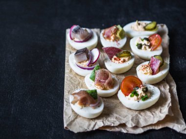 Çeşitli tepesi ile yumurta dolması. Jambon, ringa balığı, salatalık turşusu, sosis, turp, domates, kapari ve susam haşlanmış yumurta yarım üzerinde.