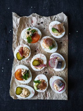 Çeşitli tepesi ile yumurta dolması. Jambon, ringa balığı, salatalık turşusu, sosis, turp, domates, kapari ve susam haşlanmış yumurta yarım üzerinde.