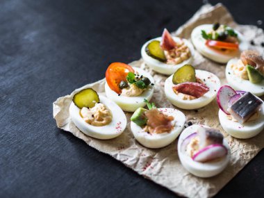 Çeşitli tepesi ile yumurta dolması. Jambon, ringa balığı, salatalık turşusu, sosis, turp, domates, kapari ve susam haşlanmış yumurta yarım üzerinde.