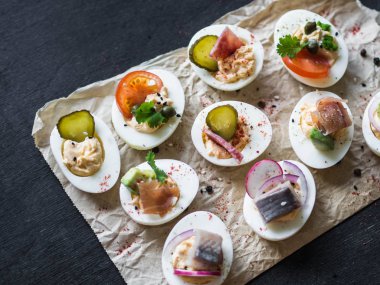 Çeşitli tepesi ile yumurta dolması. Jambon, ringa balığı, salatalık turşusu, sosis, turp, domates, kapari ve susam haşlanmış yumurta yarım üzerinde.