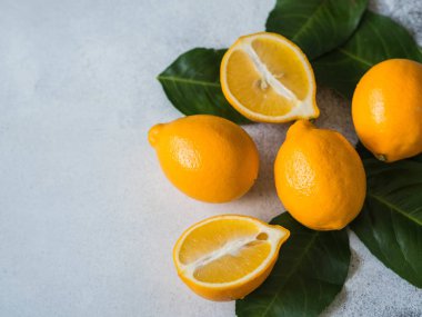 Turuncu meyeri limon gri bir arka plan üzerinde bir grup yeşil yaprakları ile.