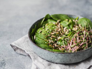 Sağlıklı yeşil salata, ıspanak, Brüksel lahanası, avokado ve mavi bir kabın içinde çeşitli tohum