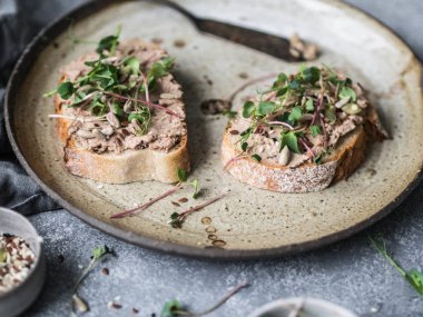 İki tost ördek ile lahanası ile beyaz ekmek üzerinde rillettes ezme ve vintage bir plaka üzerinde çeşitli tohumları Kuru Erik