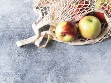 Çevre dostu bej alışveriş çantası gri bir arka plan üzerinde kırmızı elma ile. Çanta meyve ile dize. Sıfır atık, hiçbir plastik kavramı.