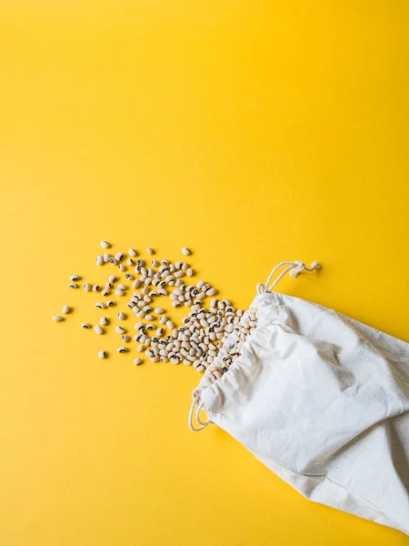 Shopping bag eco-friendly beige con fagioli su sfondo giallo. Zero rifiuti, nessun concetto di plastica . — Foto Stock