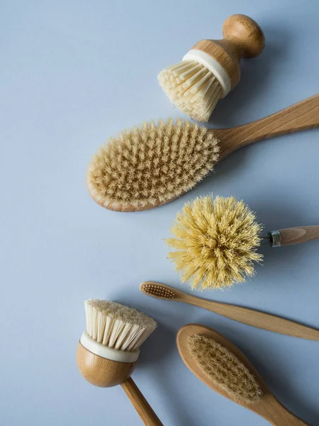 Dish washing brushes, body brush and toothbrushes on blue background. Sustainable lifestyle zero waste concept. Clean without waste. No plastic objects.