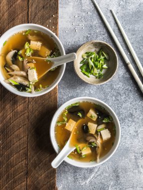 İstiridye mantar ile bir kaşık ve beyaz çubuklar gri ve ahşap arka plan üzerinde beyaz bir kase ile Japon miso çorbası. Üstten Görünüm