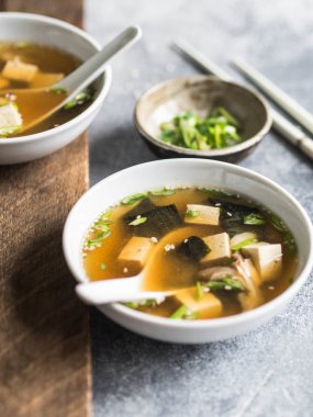 İstiridye mantar ile bir kaşık ve beyaz çubuklar gri ve ahşap arka plan üzerinde beyaz bir kase ile Japon miso çorbası.