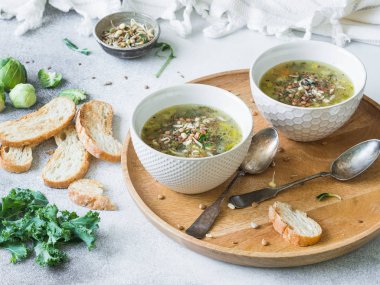 Yeşil sebze vejetaryen çorba keil, Brüksel lahanası, kabak, pırasa ile çeşitli germinated tohum ve ahşap tepsi croutons lahanası