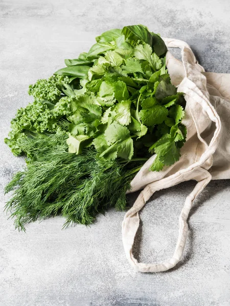 Friska gröna veganska ingredienser för matlagning. Olika örter och keil i textil väska på grå bakgrund. Produkter från marknaden utan plast. Kopiera utrymme — Stockfoto