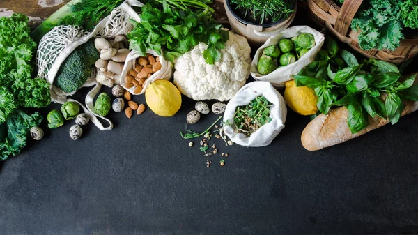 Healthy vegetarian ingredients for cooking. Various clean vegetables, herbs, nut and bread on black background. Products from the market without plastic. Flat lay. — Stock Photo, Image