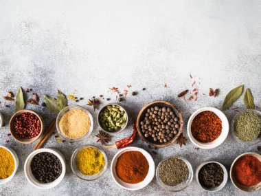 Çeşitli kuru baharat düz gri arka plan üzerinde küçük kase içinde yatıyordu. Üstten Görünüm, kopya alanı