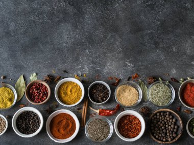 Çeşitli kuru baharat düz gri arka plan üzerinde küçük kase içinde yatıyordu. Üstten Görünüm, kopya alanı