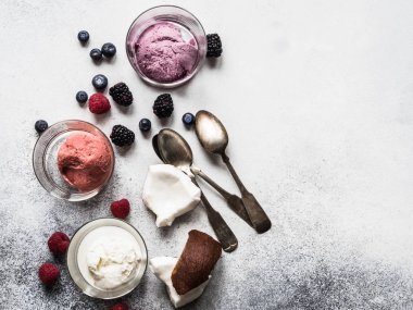 Gri bir arka plan üzerinde cam, çilek ve metal kaşık taze çilek dondurma farklı renklerini. Üstten Görünüm. kopya alanı