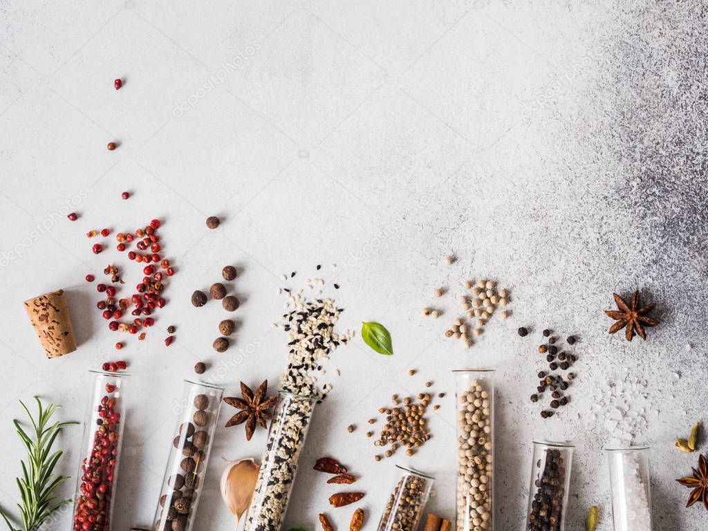 Various spices in glass test tubes and fresh herbs on gray background. Set of various spices and herbs flat lay