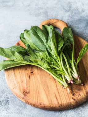 Gri bir arka plan üzerinde ahşap tahta üzerinde bahçe ıspanak taze yaprakları bir demet