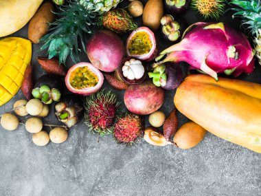 Çeşitli taze Tay meyveleri - rambutan, mango, mangosteen, longan, papaya, ejderha meyve, sapodilla, tutku meyve,, ahşap bir tepsi ve gri bir arka plan üzerinde ananas. Üst te. Kopyalama alanı