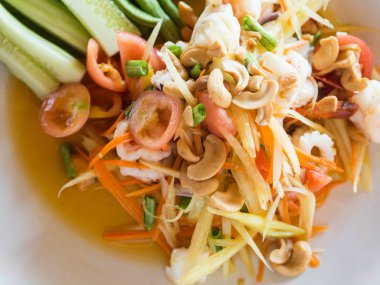 Yeşil papaya, taze sebze ve otlar, Tay restoranda tabakta deniz ürünleri ile otantik geleneksel salata