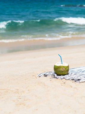 Taze bir genç hindistan cevizi mavi bir denize karşı kumlu bir plajda bir havlu üzerinde yemek için hazırdır. Tropikal tatil seyahat konsepti. Kopyalama alanı