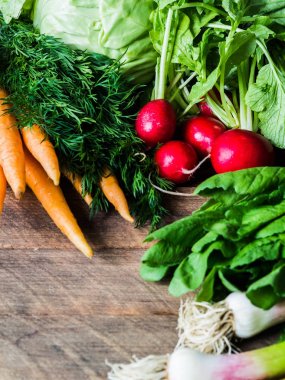 Taze Bahar sebze ve otlar - havuç, ramson, turp, dereotu, sarımsak, ahşap arka plan üzerinde lahana. Taze sebzebahar hasadı. Kopyalama alanı