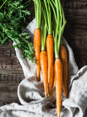 Mutfak havlusunda yeşil tepeli taze havuç kırsal ahşap arka planda.
