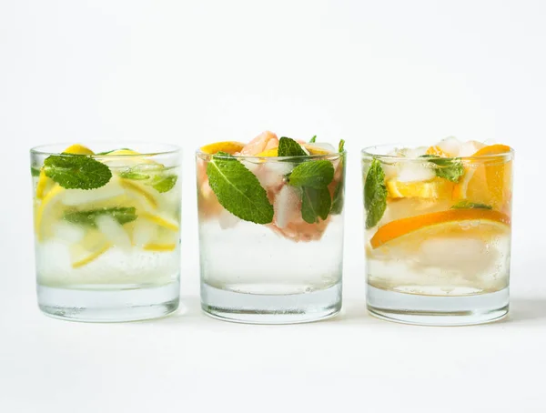 Установите летом прохладительные напитки с различными цитрусовыми и стадами в стаканах на белом фоне. Коктейль с грейпфрутом, апельсином, лимоном и льдом — стоковое фото