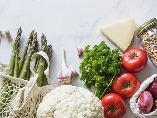 Vários alimentos frescos em pacote ecológico sobre fundo de mármore branco. Refeição orgânica saudável vegetariana do mercado. Conceito de resíduo zero — Fotografia de Stock