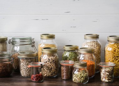 Çeşitli tahıllar ve tohumlar - bezelye bölünmüş, ayçiçeği ve kabak çekirdeği, fasulye, pirinç, makarna, yulaf ezmesi, kuskus, keten, badem, mercimek, goji, mutfakta masada cam kavanoz bulgur