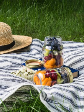 Yeşil çim ekose meyve ve çilek bir salata ile Cam kavanoz. Parkta piknik için mevsimlik sağlıklı vejetaryen gıda