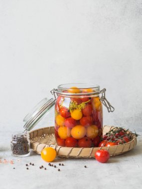 Ahşap bir arka plan üzerinde baharat ile Marine kiraz domates. Cam bir kavanozda kırmızı ve sarı kiraz domates turşusu
