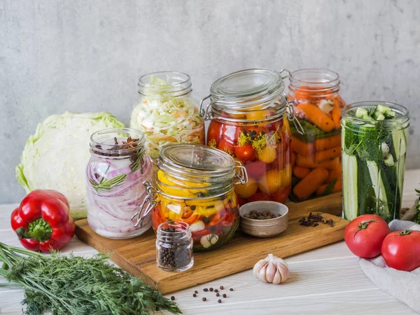 Μαγειρική τουρσί λαχανικά. Αλατίζοντας διάφορα λαχανικά σε γυάλινα βάζα για μακροχρόνια αποθήκευση. Διατηρεί τα λαχανικά σε γυάλινα βάζα. Ποικιλία που ζυμώνεται πράσινα λαχανικά στο ξύλο σανίδα — Φωτογραφία Αρχείου