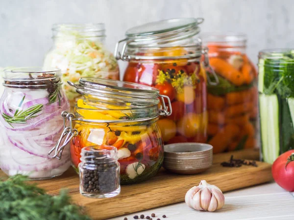 Cozinhar vegetais em conserva. Salgando várias verduras em jarros de vidro do armazenamento a longo prazo. Preserva legumes em frascos de vidro. Variedade vegetais verdes fermentados em tábua de madeira — Fotografia de Stock