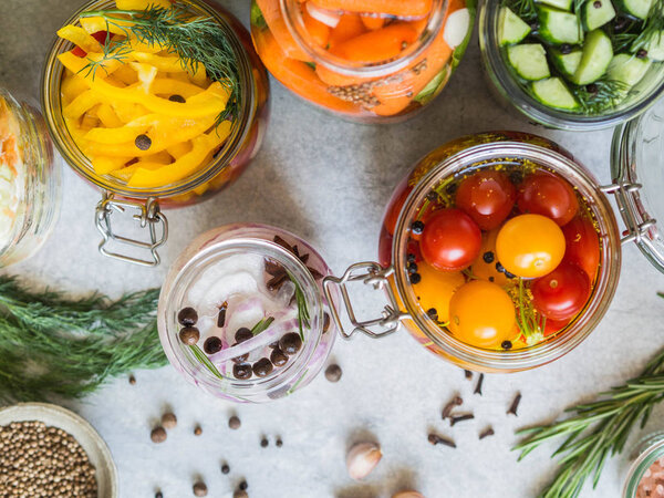 Pickled vegetables. Salting various vegetables in glass jars for long-term storage. Preserves vegetables in glass jars. Variety fermented green vegetables on table. Top view. Copy space