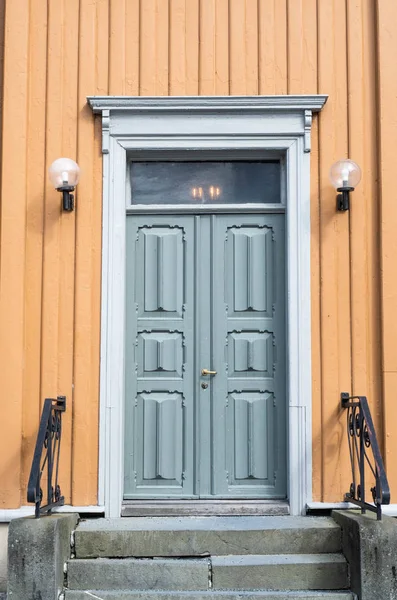 Porta vintage de madeira azul velho com varanda de pedra, trilhos e lâmpadas na fachada amarela — Fotografia de Stock