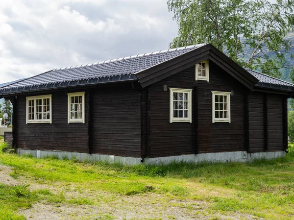 Traditional Brown Wooden Scandinavian House with White Windows at a Camping on the green lawn