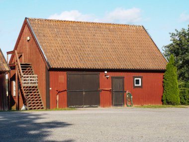 Kapısı ve merdivenli kırmızı ahşap ahır. Büyük bir hizmet bahçesinde büyük olmayan konut bina