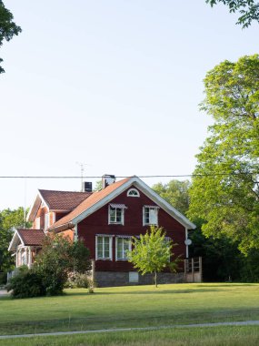 İskandinav tarzında büyük kırmızı ahşap ev, çim, çiçek yatakları, geçit