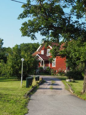 İskandinav tarzında büyük kırmızı ahşap ev, çim, çiçek yatakları, geçit