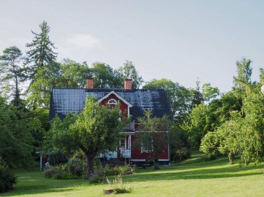 İskandinav tarzında büyük kırmızı ahşap ev, çim, çiçek yatakları, geçit
