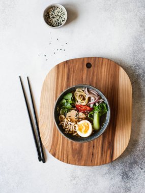 Tavuk, pak choi lahana ve gri arka plan üzerinde ahşap tahta üzerinde yumurta ile Asya Ramen erişte. Üstte görüntü.