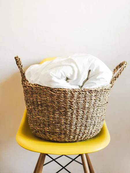 Grand panier en osier avec couverture blanche sur une chaise jaune Espace de copie — Photo